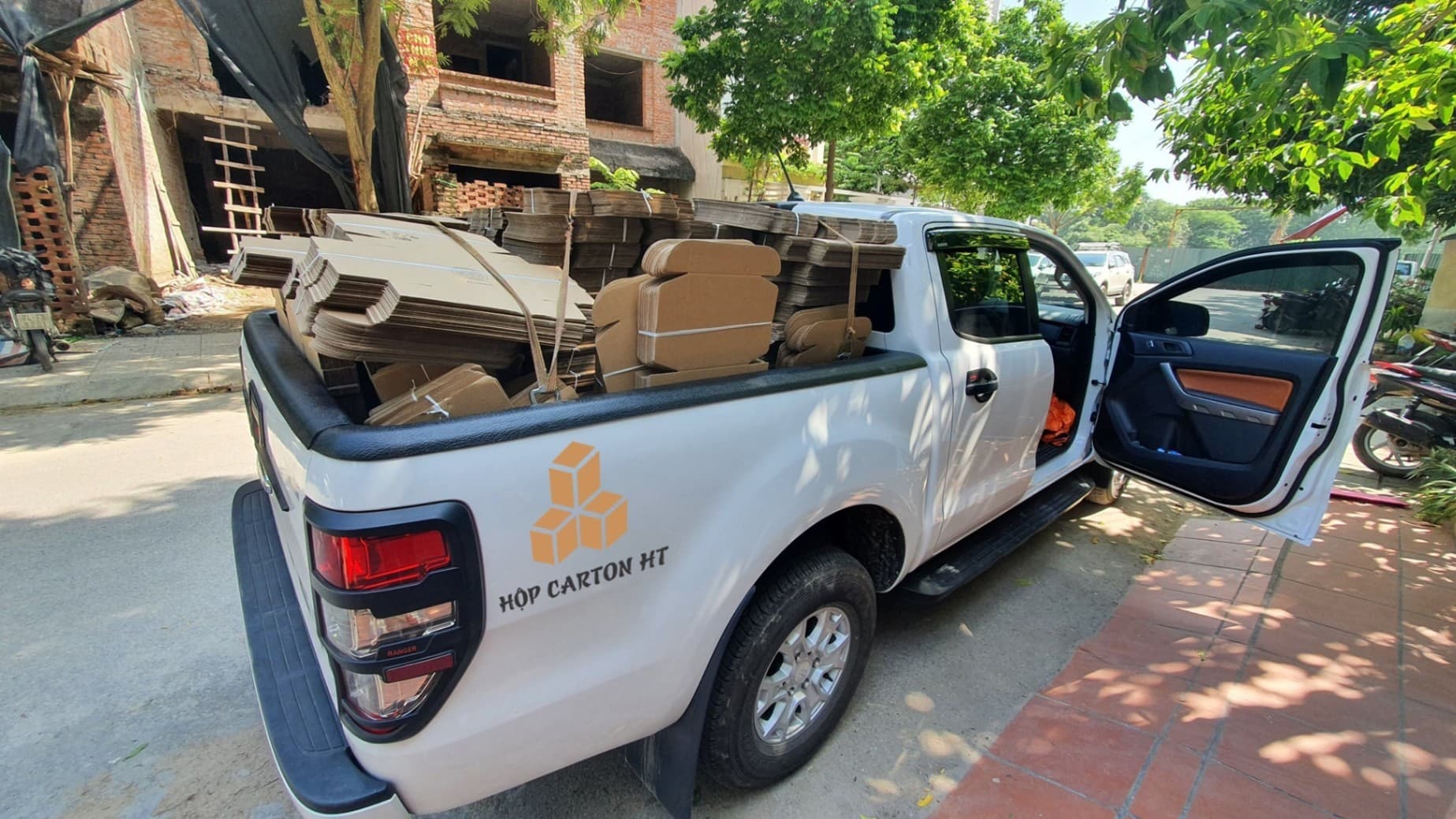 Xe bán tải dán logo Hộp Carton HT chở hộp carton